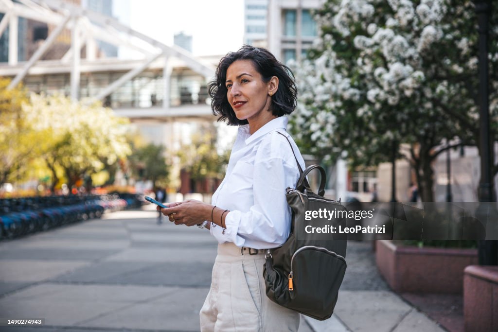Businesswoman busy on mobile phone out of the office while waiting for the bus