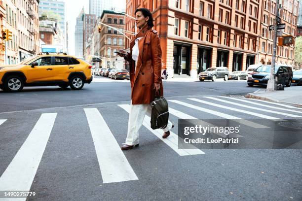 geschäftsfrau, die die straße zum büro in der innenstadt überquert - lower manhattan stock-fotos und bilder