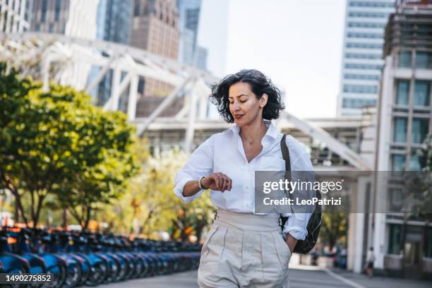 businesswoman checking the time in the street - urgency stock pictures, royalty-free photos & images