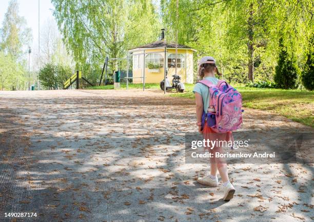 a caucasian girl, a schoolgirl with a school bag, 7 years old, goes to school across the yard along the road. - spring finland stock pictures, royalty-free photos & images