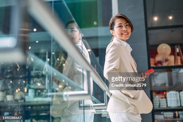 juggling devices and responsibilities: a day in the life of an asian business woman - woman holding smart phone stock pictures, royalty-free photos & images