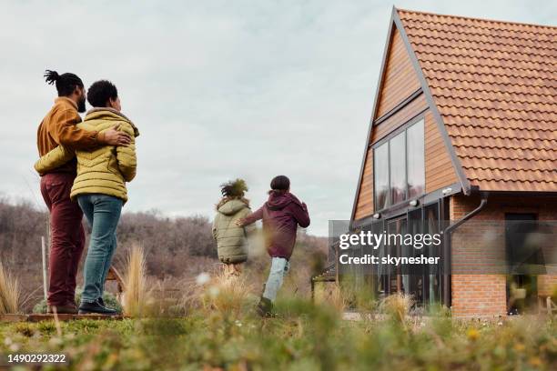 rear view of black parents looking at their kids having fun in the backyard. - family from behind stock pictures, royalty-free photos & images