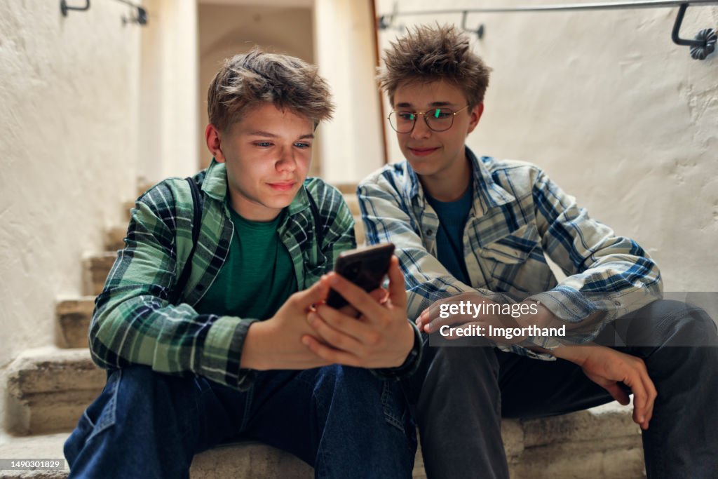 Generation z teenagers sitting on stairs and using phone