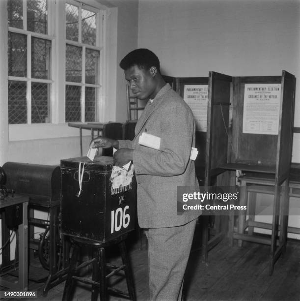 Voter casts his vote into a ballot box during the British general election, Effra Road Polling Station, Brixton, London, October 15th 1964.