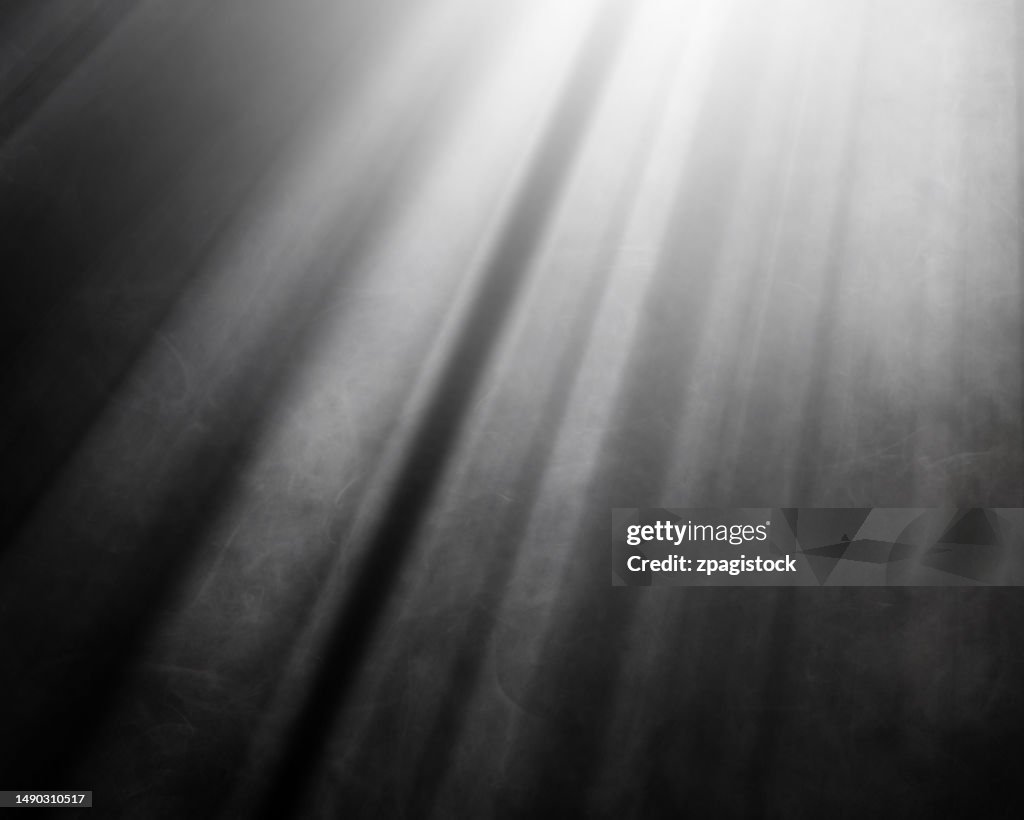 Light rays illuminating white smoke against black background