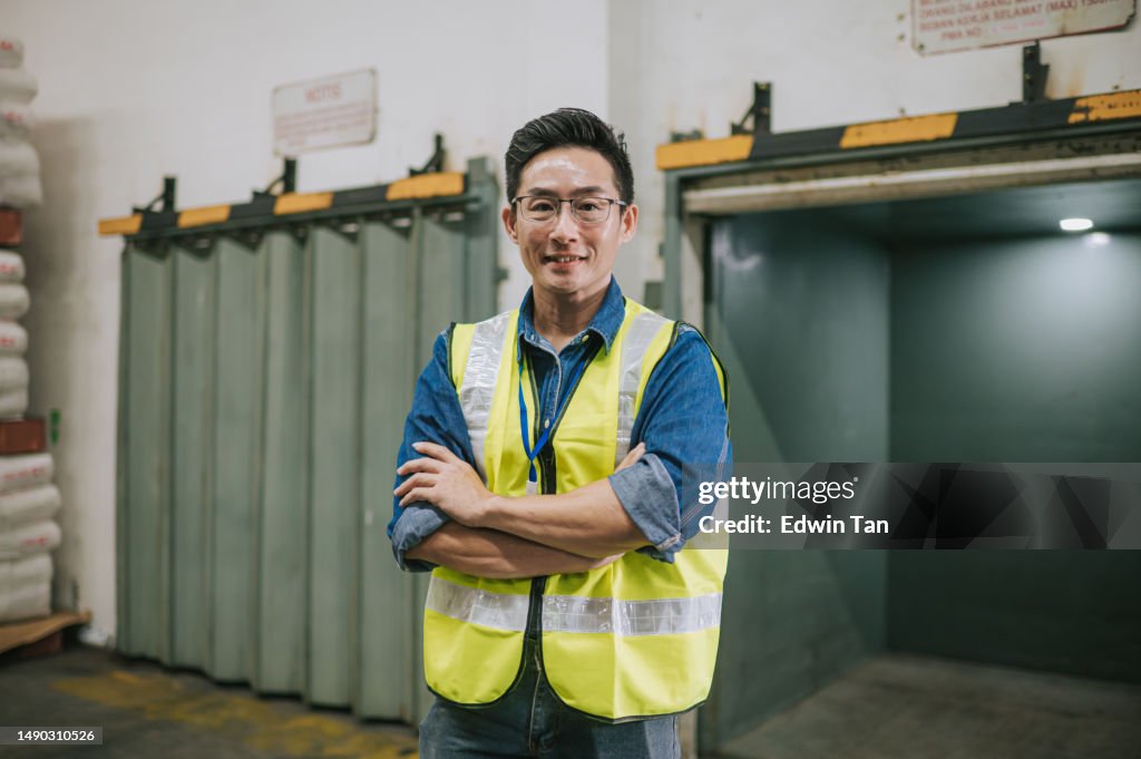 Asian Chinese Male Warehouse worker arms crossed looking at camera smiling