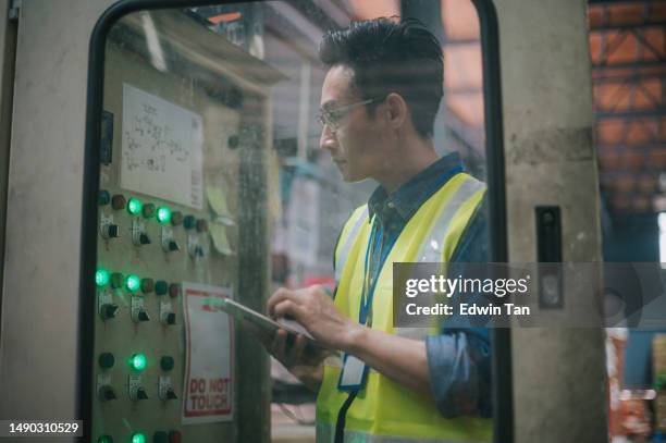 asian chinese male maintenance engineer checking on factory control panel with digital tablet - guaranteed power supply stock pictures, royalty-free photos & images