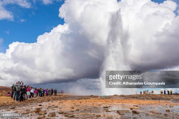 Tourists watching an erupting geyser in Haukadalur Geothermal Park on April 16, 2023 in Haukadalur, Iceland.