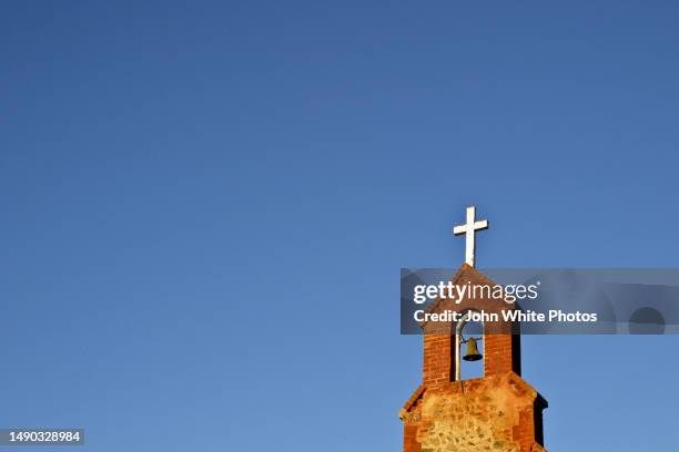 cross and bell on the top of a church steeple. - aguja chapitel fotografías e imágenes de stock