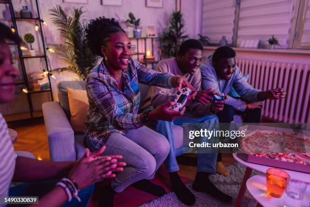 black family playing video games and eating pizza together in the living room - family game night stock pictures, royalty-free photos & images