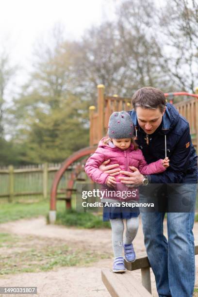 father helping her daughter to walk on the balance beam - playground balance beam stock pictures, royalty-free photos & images