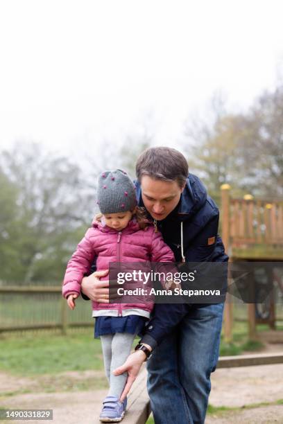 father helping her daughter to walk on the balance beam - playground balance beam stock pictures, royalty-free photos & images