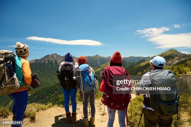 hikers stand on top of a mountain looking at view. - hiking rucksack stock pictures, royalty-free photos & images