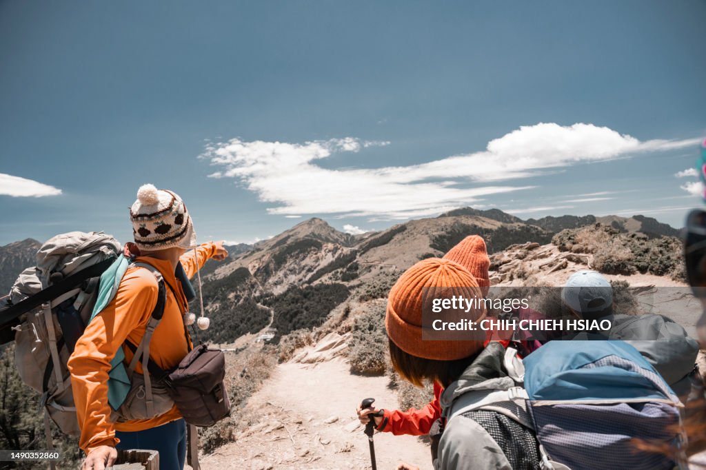 Hikers stand on top of a mountain looking at view.