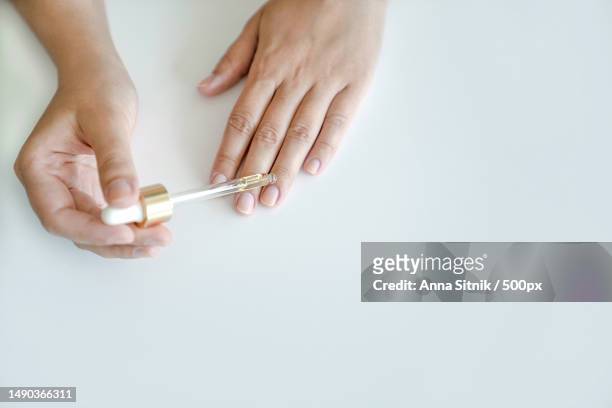 woman holds pipette with oil to apply to her nails for treatment and strengthening of nails,turkey - nagelhaut stock-fotos und bilder