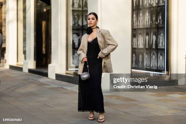 Bella Emar wears black dress, beige blazer, Paco Rabanne bag, heeled sandals, flower choker on May 15, 2023 in Berlin, Germany.