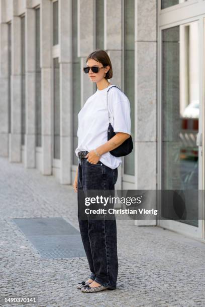 Jacqueline Zelwis wears white ONWEEKENDS T-Shirt, dark Calvin Klein jeans, Pretty Ballerinas shoes, Prada bag, Marc Jacobs sunglasses on May 15, 2023...