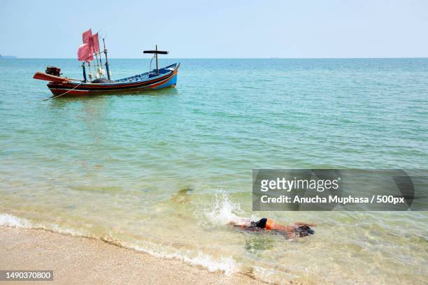 a boy snorkeling in sea with fishing boat moored on the beach,songkhla,thailand - songkhla province stock pictures, royalty-free photos & images