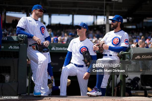 Ian Happ, Cody Bellinger, and Dansby Swanson of the Chicago Cubs prepare to the field in a game against the Los Angeles Dodgers at Wrigley Field on...