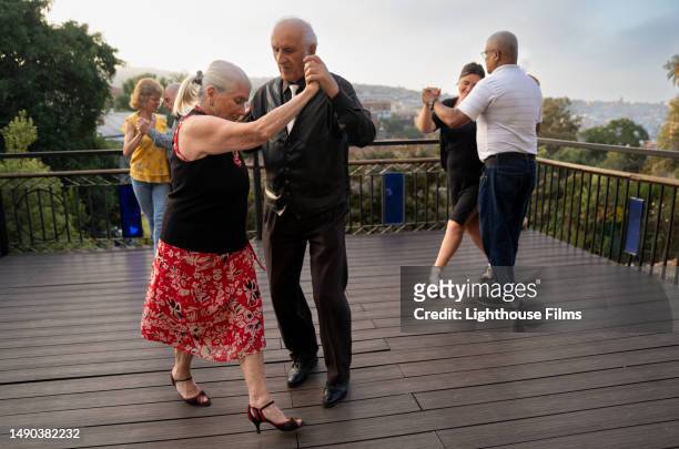group of senior couples dancing together with partners on a rooftop deck with stunning view - senior hobbies stock pictures, royalty-free photos & images