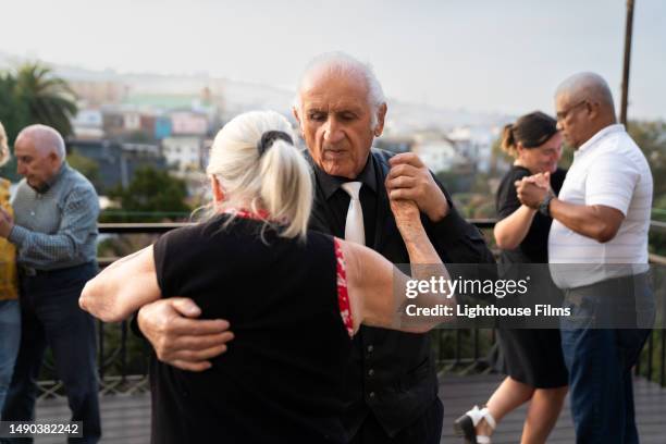 mature adult male appears focused while learning how to ballroom dance with their partner outside - danse de salon photos et images de collection