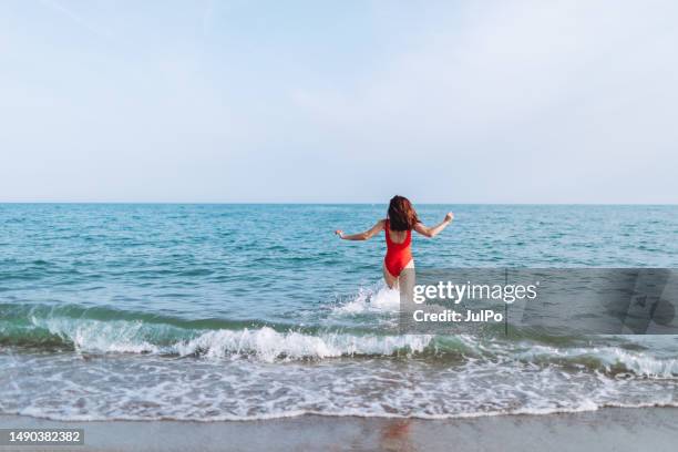 jeune femme en maillot de bain rouge s’amusant à la mer - maillot de bain femme photos et images de collection