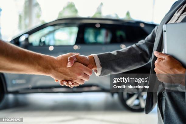 l'acquirente dell'auto stringe la mano al venditore nella concessionaria auto - venditore di automobili foto e immagini stock
