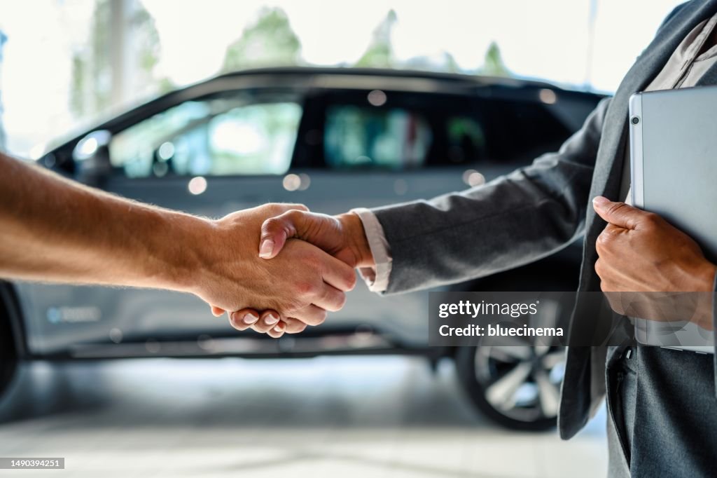 Buyer of the car shaking hands with the seller in auto dealership