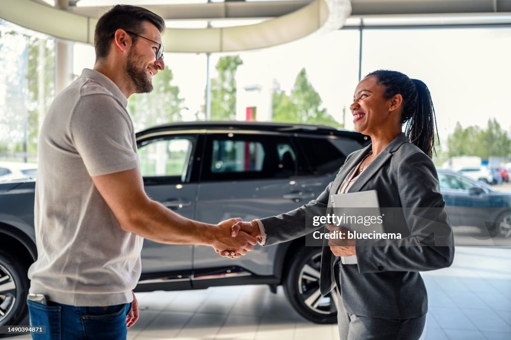 Buyer of the car shaking hands with the seller in auto dealership