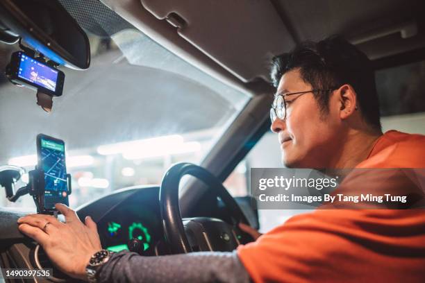 young handsome asian man using gps navigation on smartphone while driving a car - navigational equipment stock pictures, royalty-free photos & images