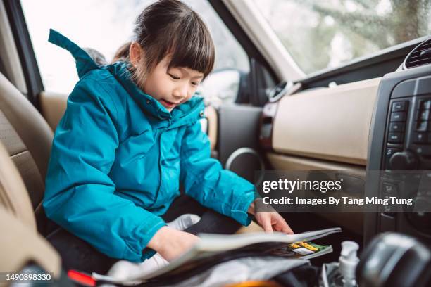 lovely cheerful girl in school uniform reading book in the car while waiting for the school open in the morning - front passenger seat stock pictures, royalty-free photos & images