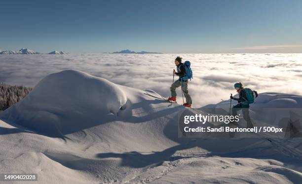 two people are hiking on a snowy mountain,srednja vas v bohinju,slovenia - slovenia winter stock pictures, royalty-free photos & images