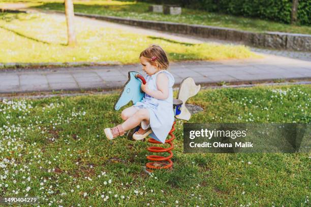 happy little girl riding horse in playground - like a child in a sweet shop stock pictures, royalty-free photos & images