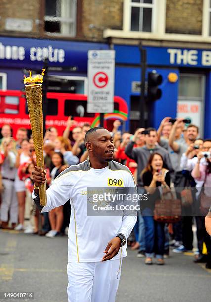In this handout image provided by LOCOG, Torchbearer 090 Dylan Mills aka Dizzee Rascal carries the Olympic Flame on the Torch Relay leg between the...
