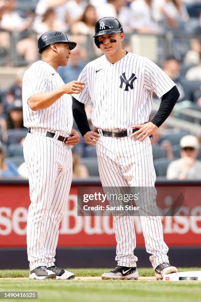 Third base coach Luis Rojas of the New York Yankees talks with Anthony Rizzo during the sixth inning against the Tampa Bay Rays at Yankee Stadium on...