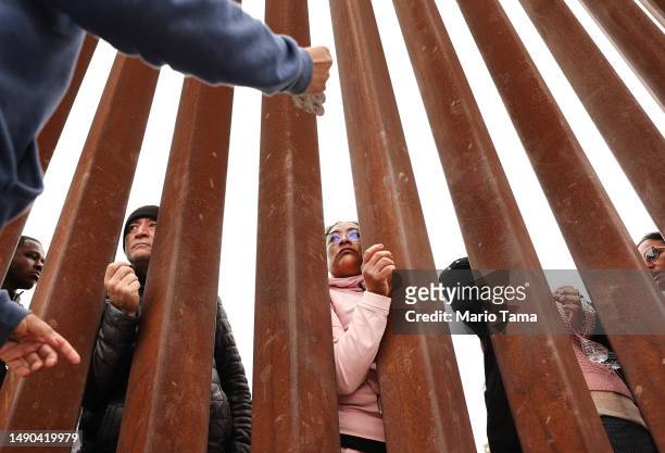 Immigrants seeking asylum in the U.S., who are stuck in a makeshift camp amongst border walls between the U.S. And Mexico, look through the border...