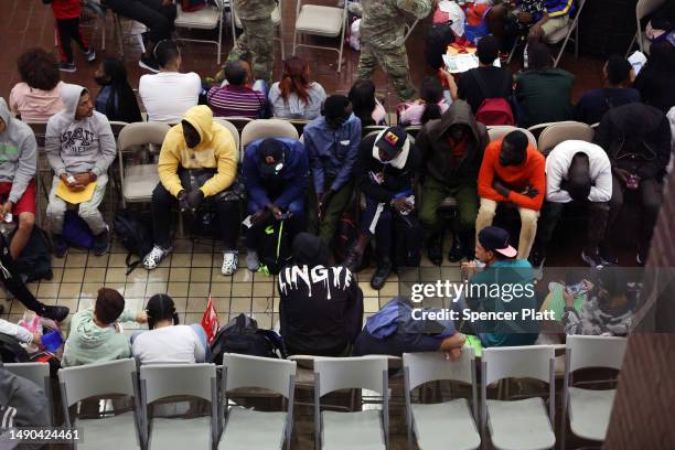 Newly arrived asylum seekers wait in a holding area at the Port Authority bus terminal before being sent off to area shelters and hotels on May 15,...