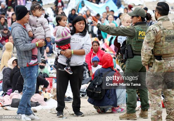 Border Patrol agent speaks to immigrants before they are transported from a makeshift camp amongst border walls, between the U.S. And Mexico, on May...
