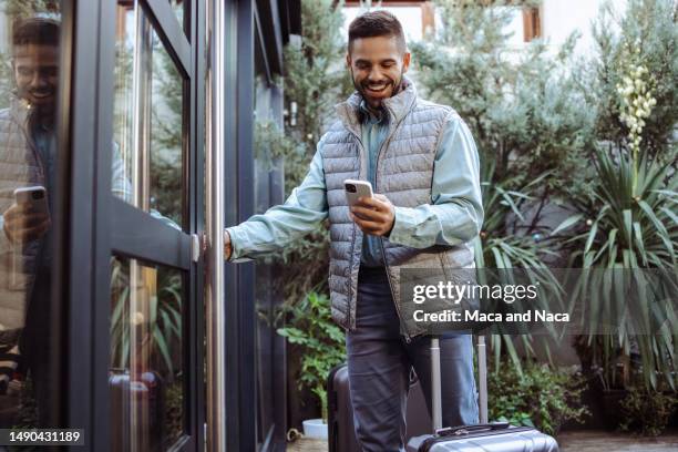 young man with suitcase using smart phone in front of the rented apartment - pin entry stock pictures, royalty-free photos & images