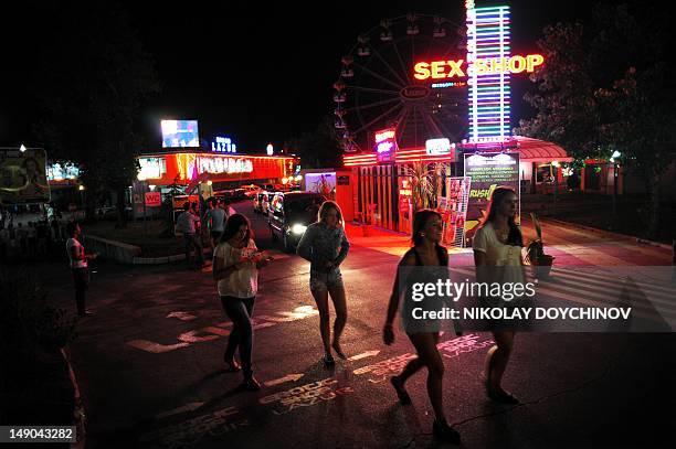 Diana Simeonova Tourists walk at night on a street in the Black Sea resort of Sunny Beach, near the city of Bourgas on July 21, 2012. Sunbathing,...