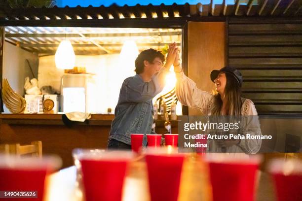 friends celebrating victory at beer pong - beer pong stock pictures, royalty-free photos & images