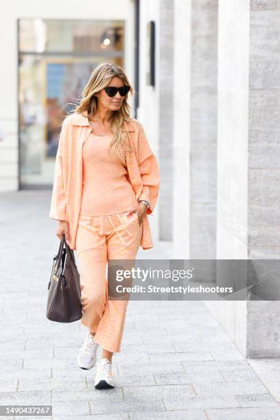 Influencer Gitta Banko, wearing a orange colored knit blouse, knit top and knit pants by Gitta Banko, white sneakers by Premiata, sunglasses by...