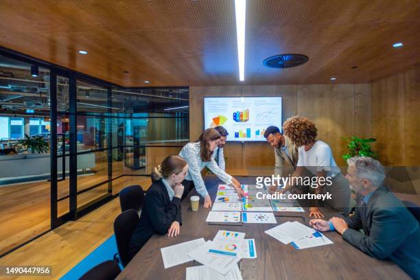 paperwork and group of peoples hands on a board room table at a business presentation or seminar. - performance collective stockfoto's en -beelden