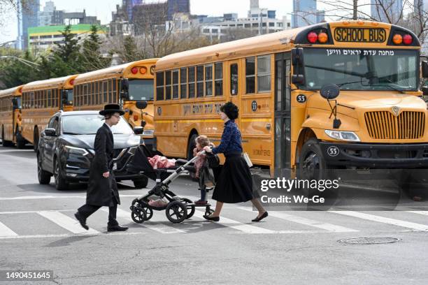 jewish hasidic family crossing a street in brooklyn. several yellow school buses in the background. - hasidic woman stock pictures, royalty-free photos & images