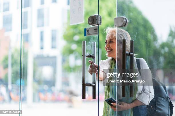 donna di 50-55 anni che apre la porta - aprire foto e immagini stock