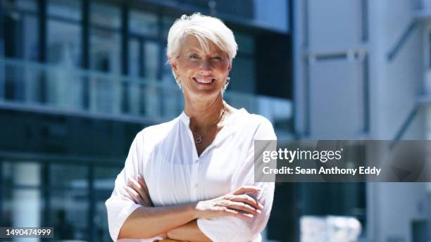 senior business woman with arms crossed in city, confidence and and happy executive in portrait with smile outdoor. company ceo, corporate female in urban street with professional career mindset - geriatrie stockfoto's en -beelden