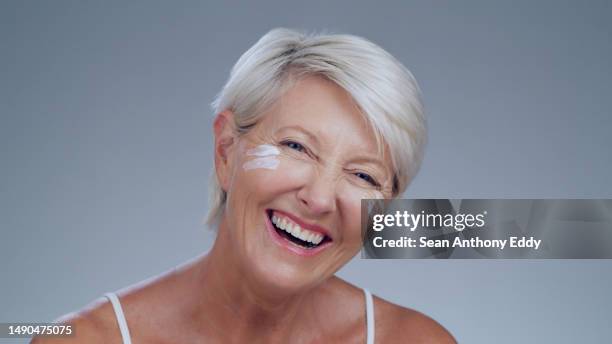 ritratto, cura della pelle e crema con una donna anziana in studio su uno sfondo grigio che sembra felice o sicura di sé. sorridi, bellezza e lozione per il viso con una modella matura che si sente positiva mentre ride - older woman happy smile foto e immagini stock