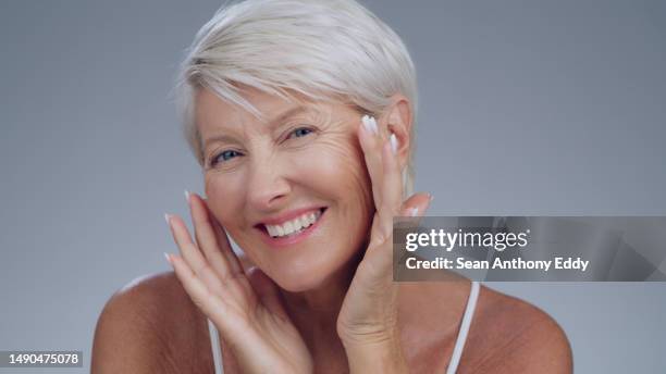 portrait, smile and senior woman with skincare, beauty and grooming against a grey studio background. face, mature female person and model with happiness, cosmetics and organic facial with confidence - model smile stockfoto's en -beelden