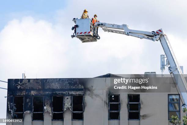 Firefighters survey the roof after a fire at Loafers Lodge on May 16, 2023 in Wellington, New Zealand. At least 10 people are dead and many more are...