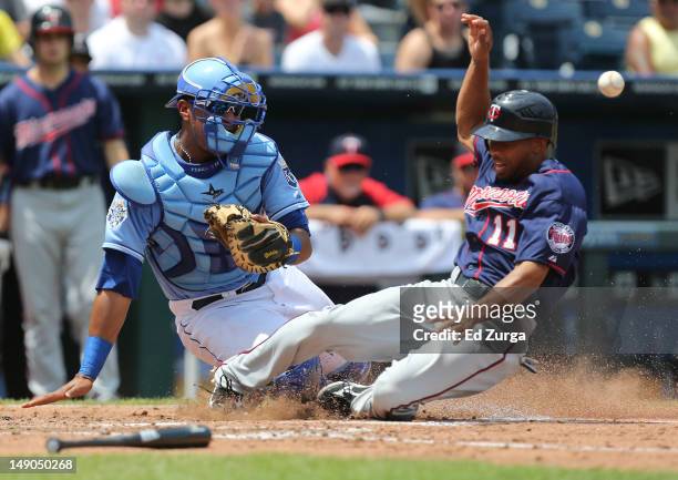 Ben Revere of the Minnesota Twins slides into home safely as Salvador Perez of the Kansas City Royals waits for the throw in the third inning at...
